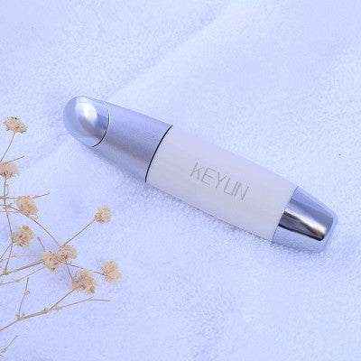 Dark Circles Beauty Home Eye Care Device in white and silver on soft fabric background.