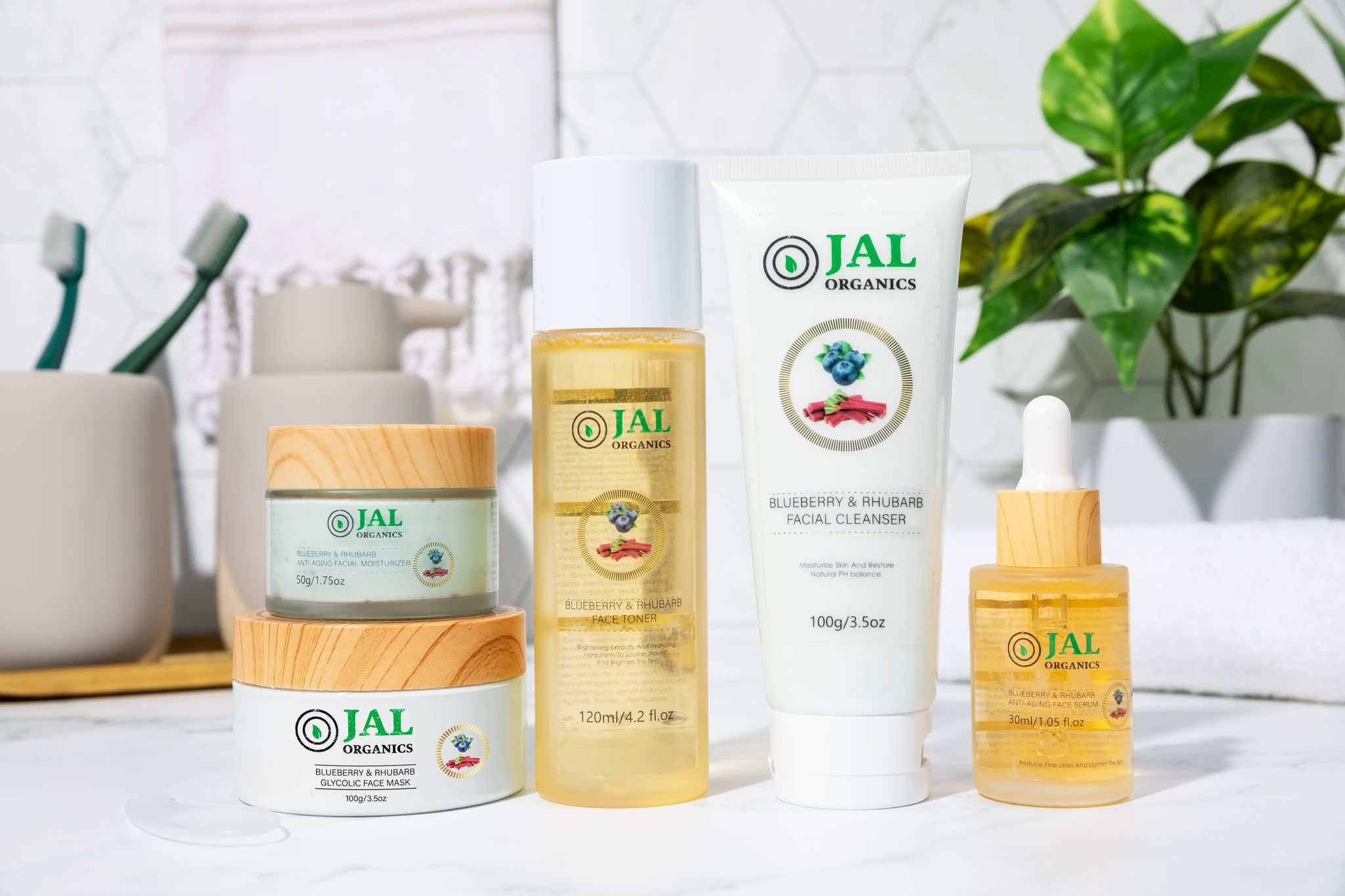 5-piece blueberry rhubarb skin care set by Jal Organics on white background with plant.