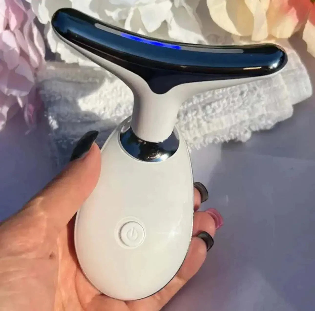 Handheld white and silver beauty device for anti-wrinkle treatment held in hand