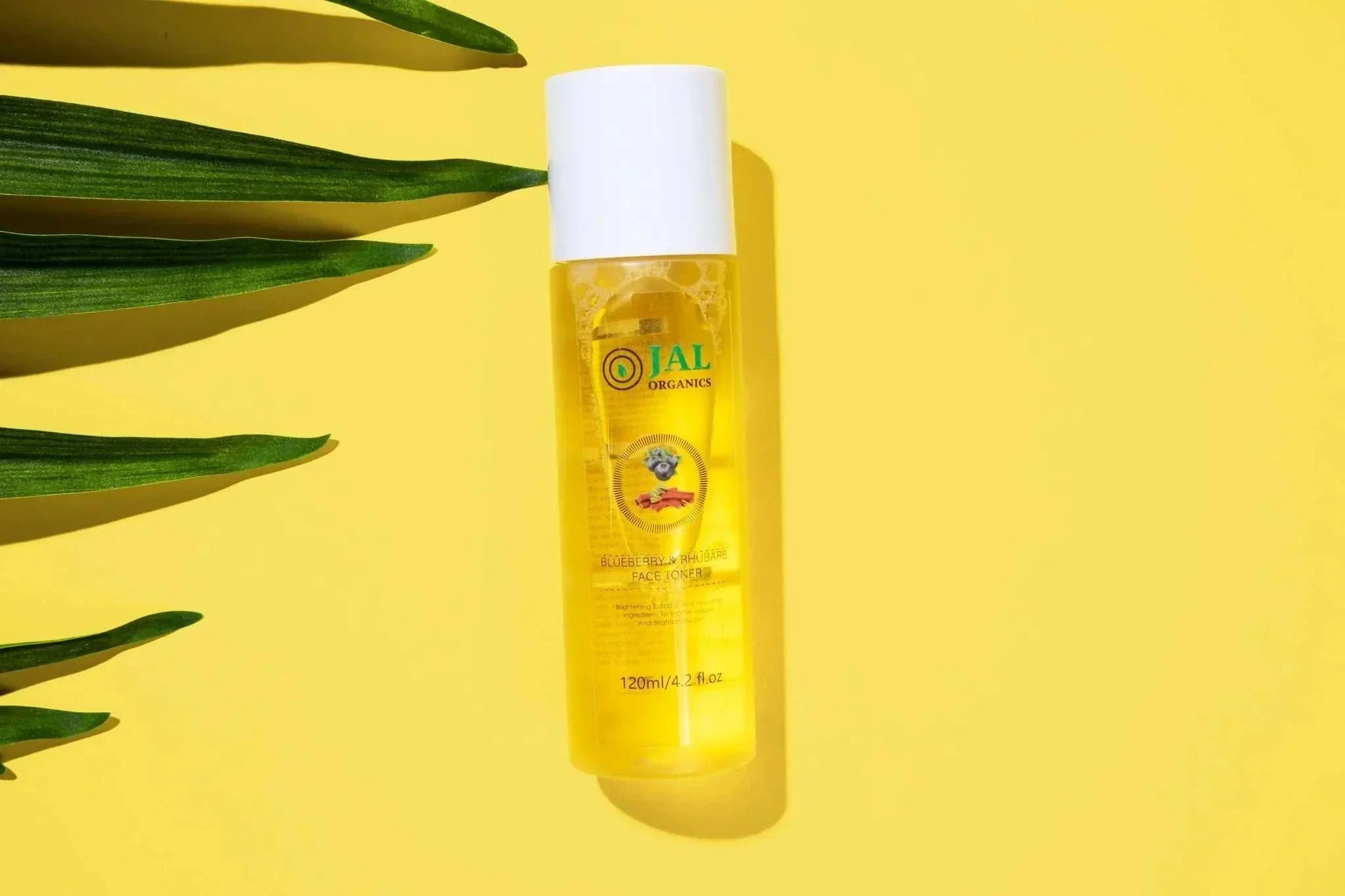 Jal Organics blueberry rhubarb facial toner bottle on yellow background.