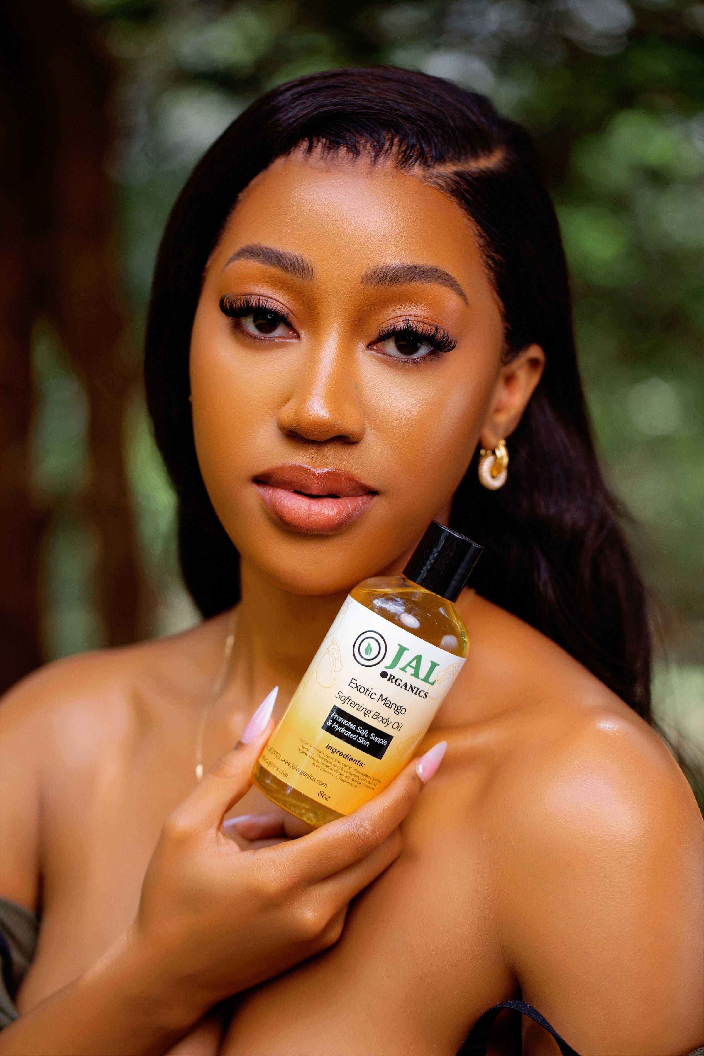 Exotic Mango Body Oil held by a woman with soft, glowing skin, showcasing a tropical and hydrating skincare product.