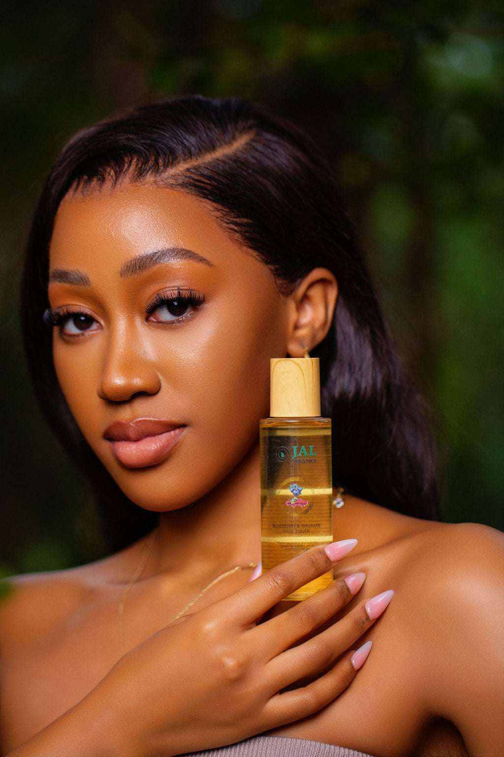 Blueberry and Rhubarb Toner held by woman with glowing skin in natural setting.