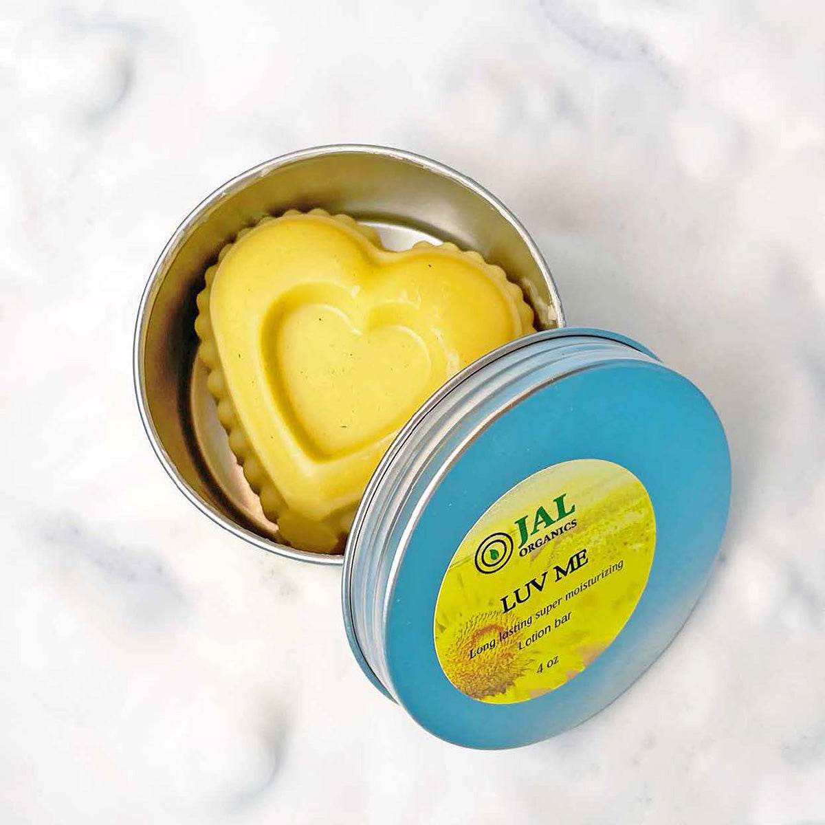 Heart-shaped Luv Me Lotion Bar in reusable tin for soft, hydrated skin.